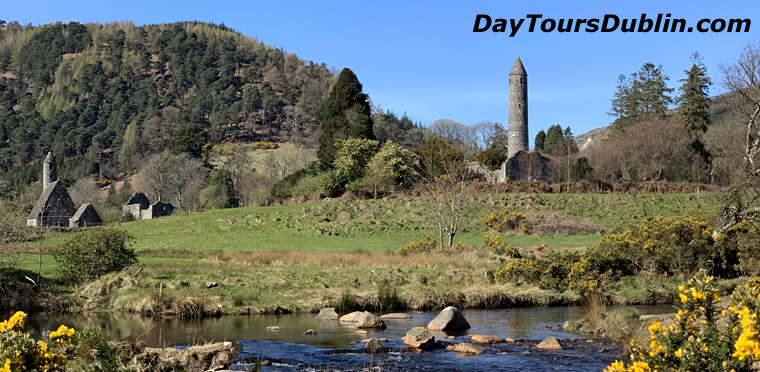 Glendalough round tower and St Kevin's Church beside a rocky stream, with wooded Wicklow hills behind